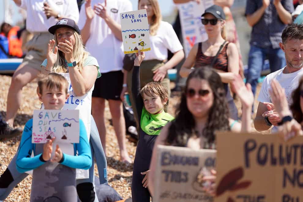 People hold up placards as Surfers Against Sewage hold a protest in Brighton (Gareth Fuller/PA)