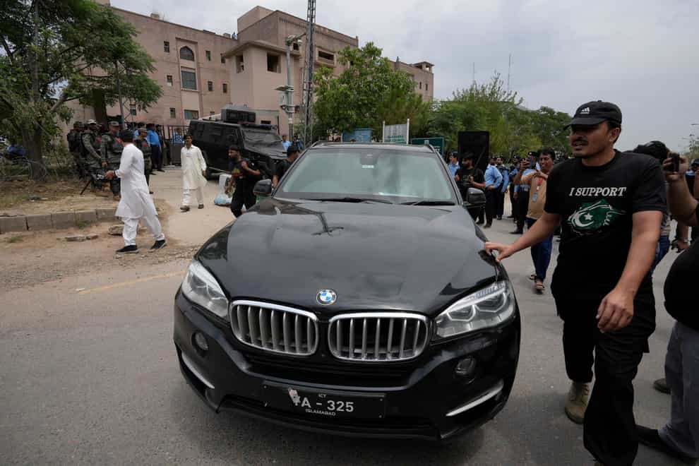 Security personnels clear way for a vehicle carrying the Pakistan’s former leader Imran Khan arrives to appear in a court, in Islamabad (AP)