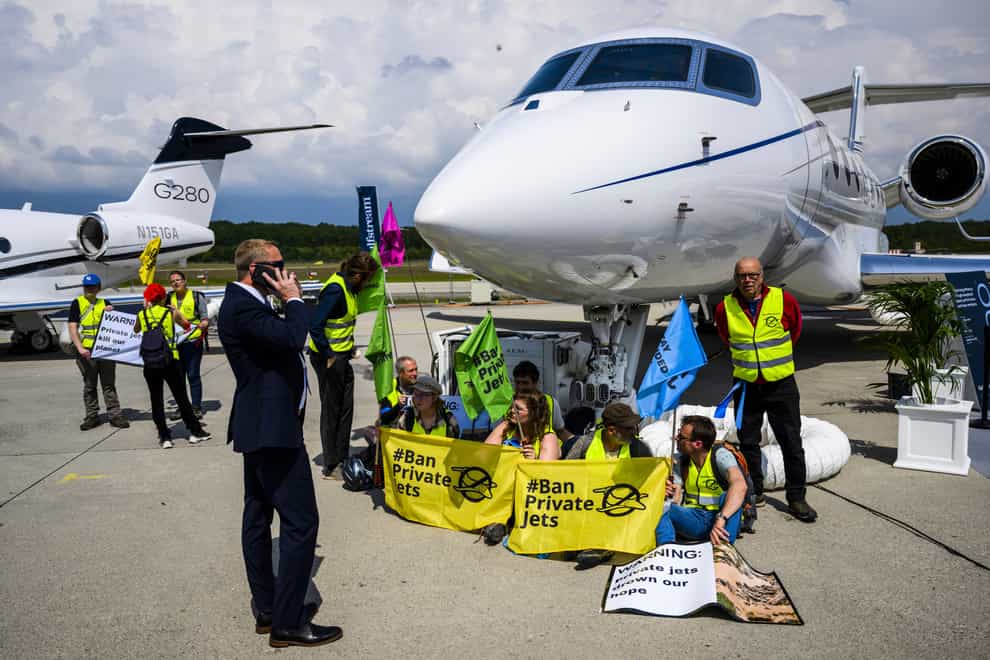 Environmental activists from Stay Grounded and Greenpeace protest by being handcuffed to a aircraft during the European Business Aviation Convention and Exhibition (EBACE), at the Geneve Aeroport in Geneva, Switzerland on Tuesday, May 23, 2023 (Laurent Gillieron/Keystone via AP/PA)