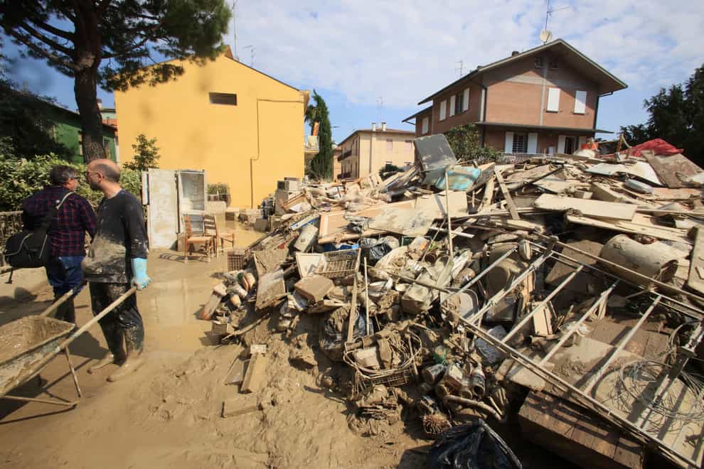 Volunteers clear mud as household goods are piled on the side of a street in Faenza, Italy, on Monday, May 22, 2023 (Michele Nucci/LaPresse via AP/PA)