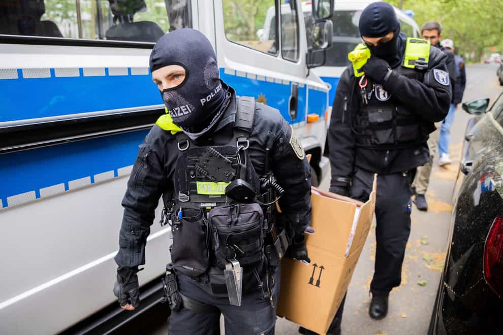 Police officers carry a cardboard box to a vehicle after a raid in Berlin (Christoph Soeder/dpa via AP)