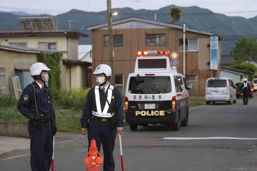 Police officers stand guard on a street leading to a building where a man was holed up in Nakano, central Japan (Kyodo News/AP)