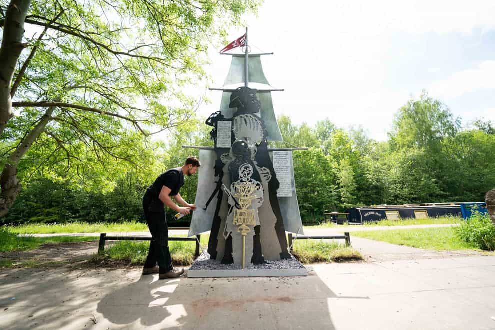 Artist Luke Perry repaints part of his sculpture, Black British History is British History, by the Soho Loop Canal in Winson Green, Birmingham after it was vandalised with a racial slur (Jacob King/PA)