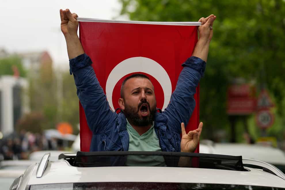 A supporter of the President Recep Tayyip Erdogan holding a Turkish flag shouts slogans outside AK Party offices in Istanbul, Turkey (Khalil Hamra/AP/PA)