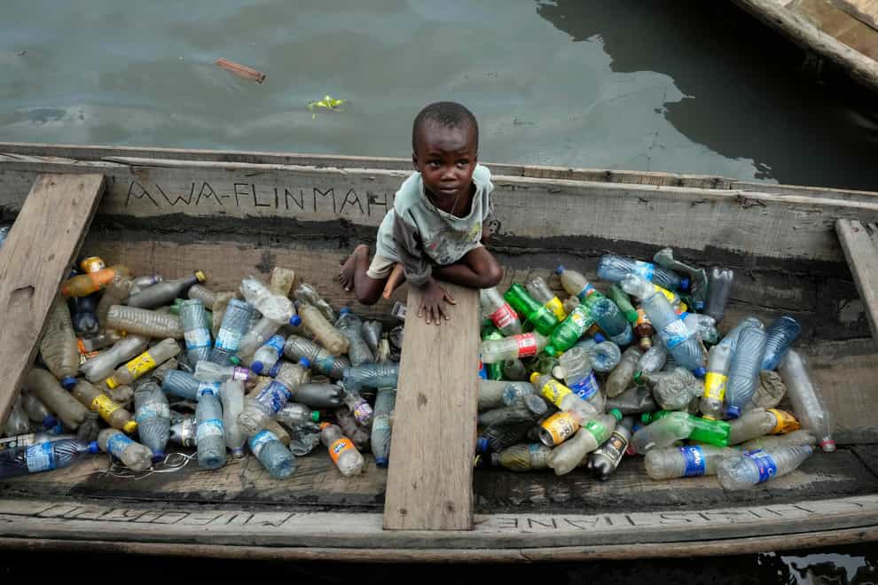 A child sells plastic bottles in Makoko in Lagos, Nigeria (AP)