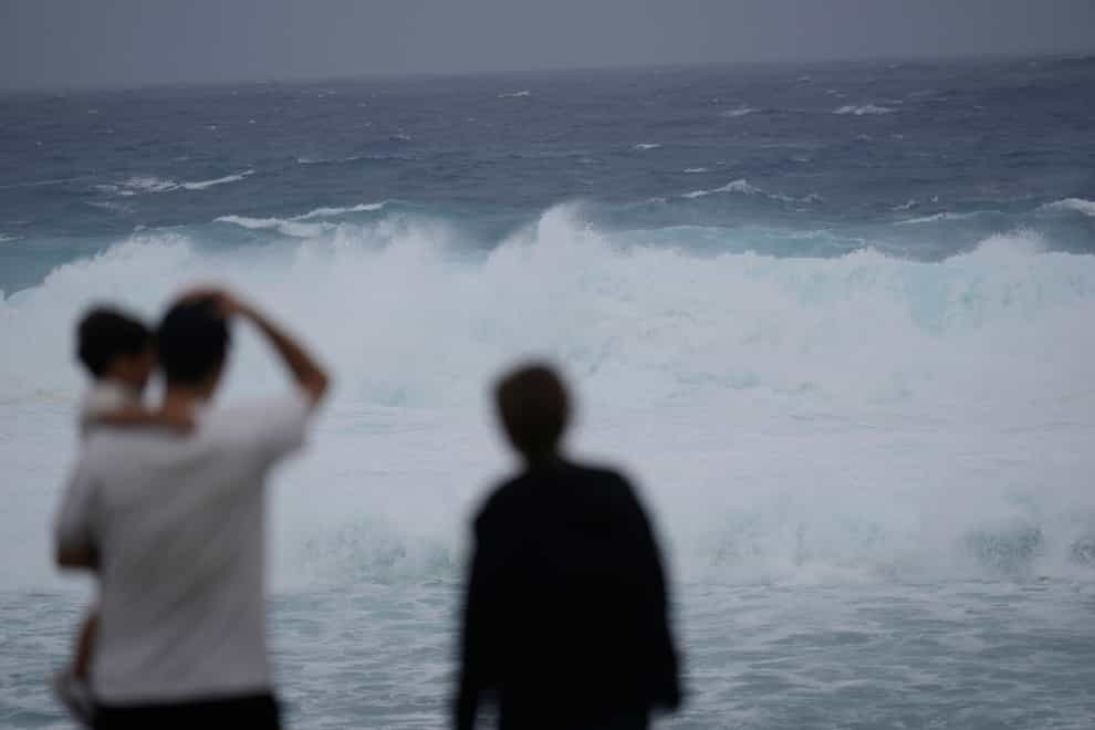 Family members watch waves affected by a severe weather system in Itoman, southern Japan (AP)