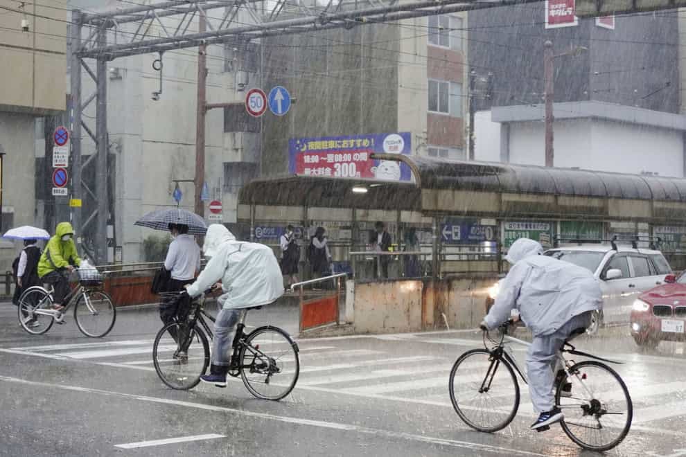 People make their way in strong rain in Kochi, southern Japan (Kyodo News via AP)