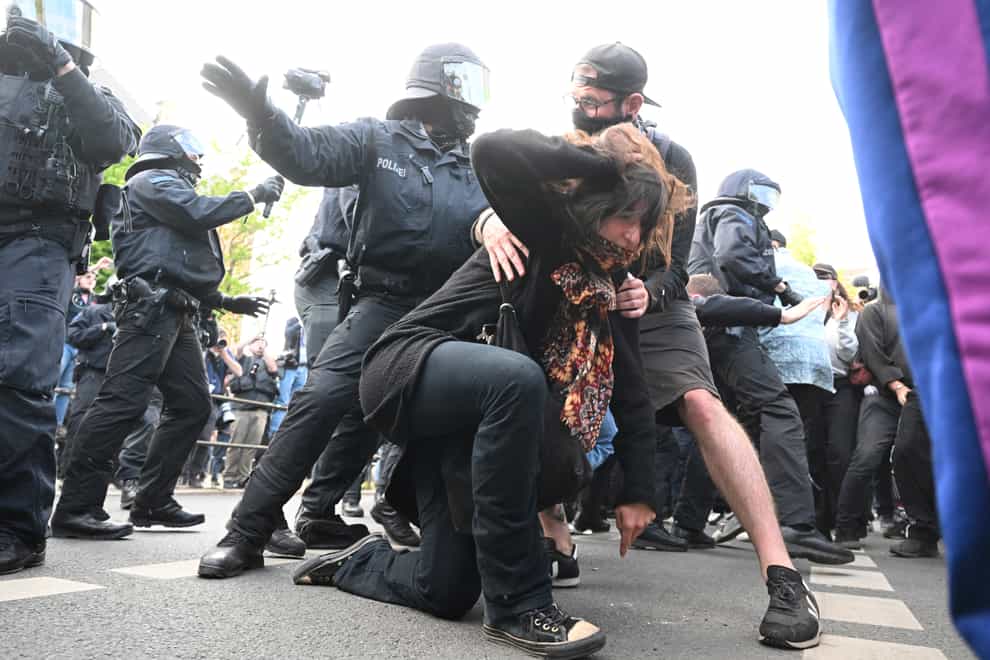 Police officers react with a woman during a left-wing demonstration, in Leipzig, Germany, Saturday, June 3, 2023. The demonstration is against the verdict in the trial of Lina E. The Dresden Higher Regional Court sentenced the student to five years and three months imprisonment. (Robert Michael/dpa via AP)