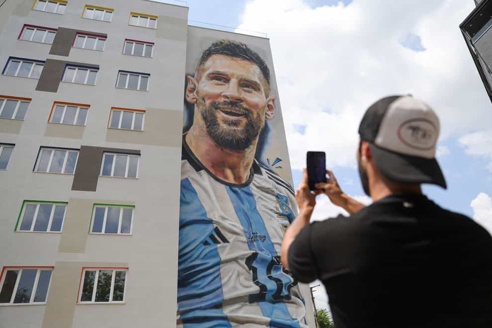 Argentinian street artist Maximiliano Bagnasco takes a photo of a mural portraying Argentinian footballer Lionel Messi, that he painted, in Tirana, Albania (Llazar Semini/AP)