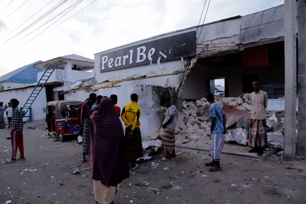 Somalis stand stand outside the destroyed Pearl Beach hotel (AP)