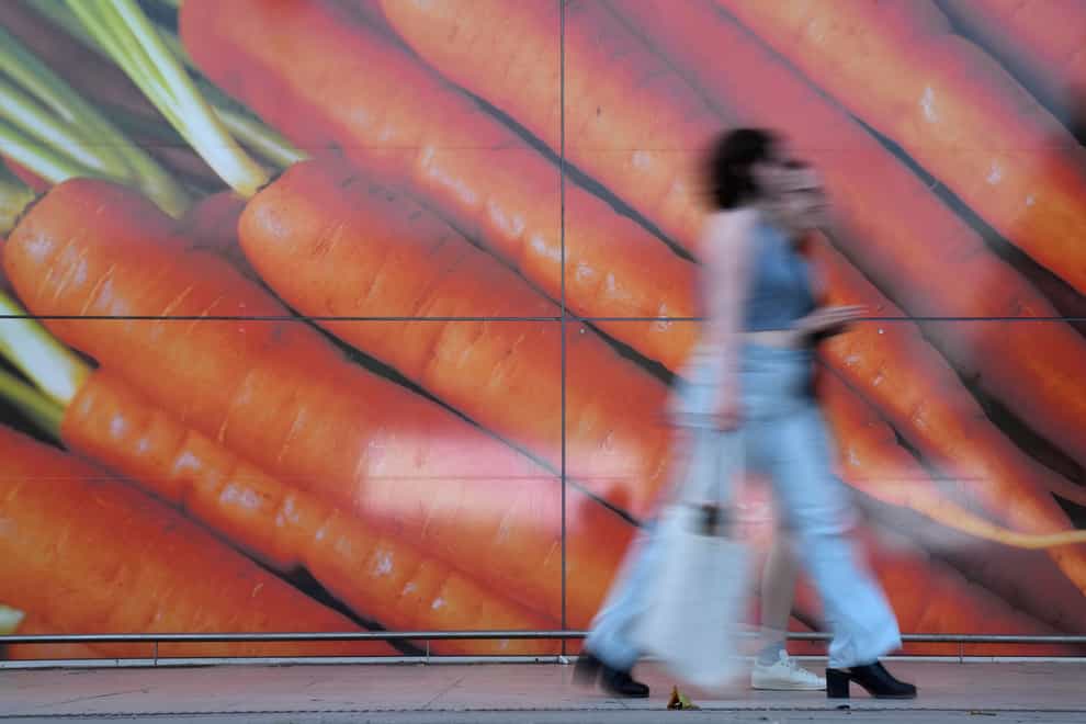 Shoppers walk past a large poster outside a supermarket (AP)