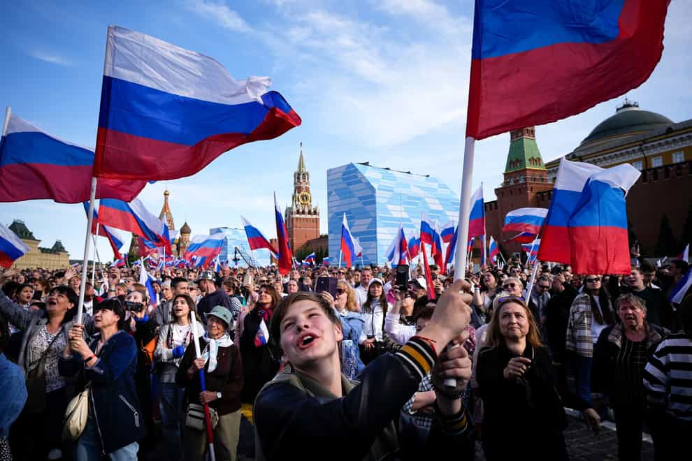 Thousands of people wave Russian national flags in Red Square (Alexander Zemlianichenko/AP)