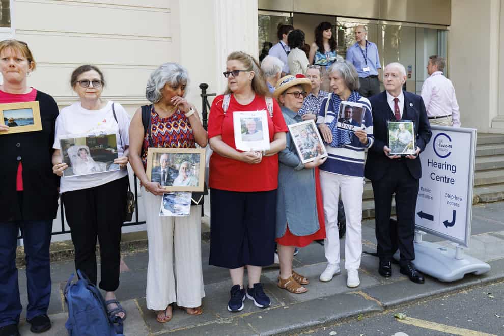 People hold pictures of loved ones lost during the pandemic outside the UK Covid-19 Inquiry at Dorland House in London (Belinda Jiao/PA)