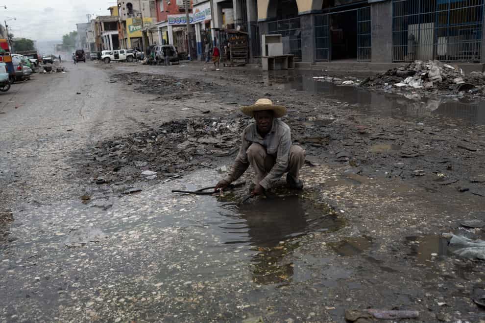A man collects water from a puddle in downtown in Port-au-Prince, Haiti, Friday, June 2, 2023. (AP Photo/Ariana Cubillos)
