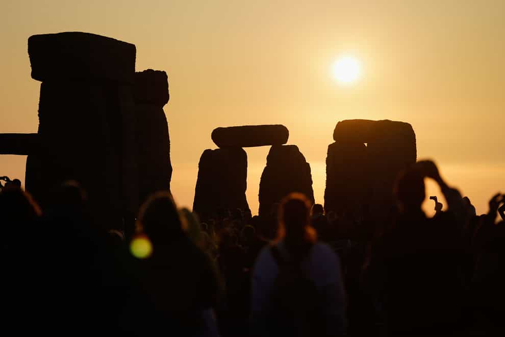 The sun rises behind the stone circle at Stonehenge in Wiltshire where people gathered to mark in the Summer Solstice (Andrew Matthews/PA)