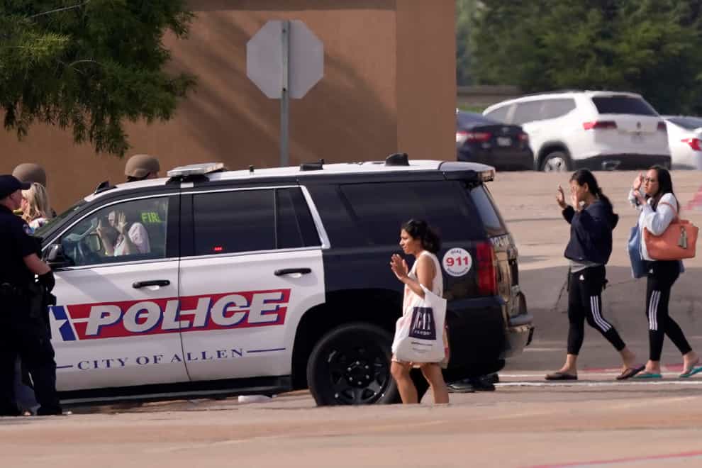People raise their hands as they leave a shopping centre after a shooting on May 6 in Allen, Texas (LM Otero/AP)