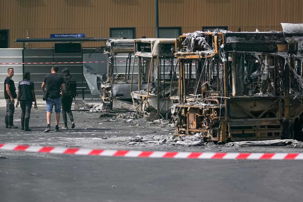 Police investigators examine charred buses after a third night of unrest at a depot in Aubervilliers near Paris (Michel Euler/AP)