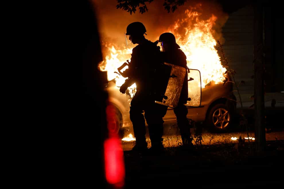 Riot police stand near a burning car in the La Meinau neighborhood of Strasbourg, eastern France (Jean-Francois Badias/AP)
