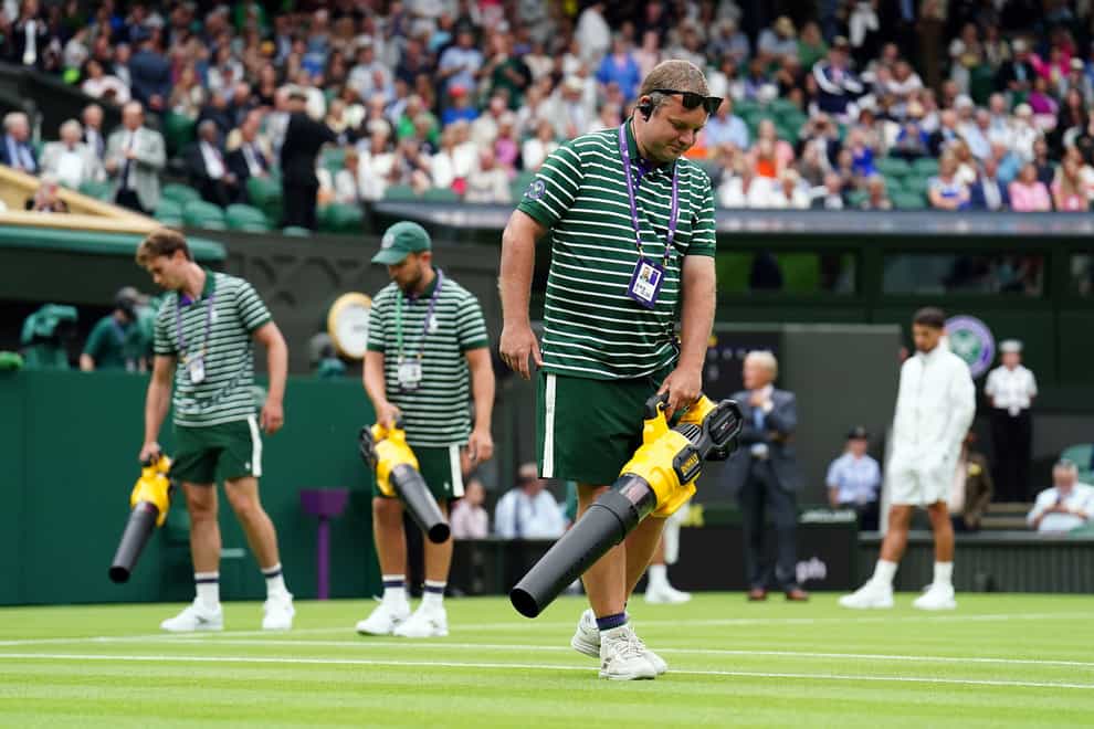 Ground staff use leaf blowers to attempt to dry the grass on Centre Court (Zac Goodwin/PA)