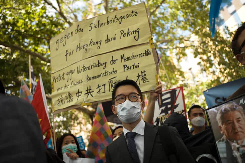 Hong Kong activist Nathan Law, centre, protests during the visit of Chinese foreign minister Wang Yi to Germany in 2020 (Markus Schreiber/AP)