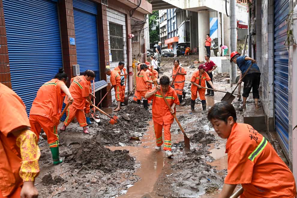 Workers clean up silt and mud along a street in the Wanzhou district of Chongqing (Xinhua via AP)