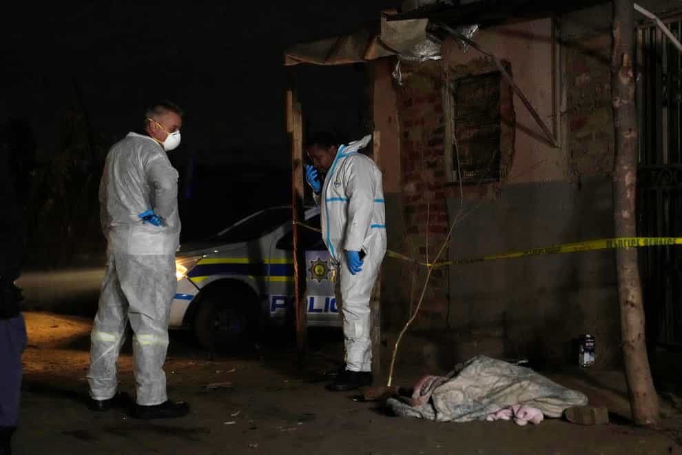 Police stand near a covered body in the Angelo settlement in Boksburg, South Africa (Themba Hadebe/AP)