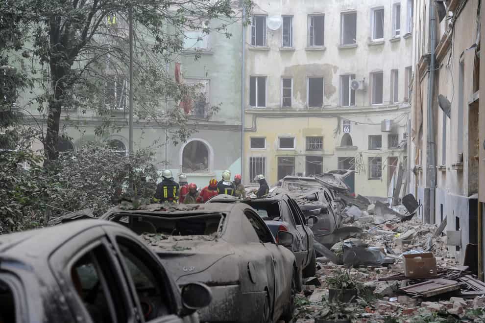 Emergency service workers gather outside damaged buildings as search for victims continues following a Russian missile attack in Lviv (Mykola Tys/AP)