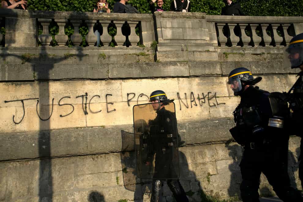 Police patrol past graffiti reading ‘Justice for Nahel’ as youths gather on Concorde Square during a protest in Paris (Lewis Joly/AP)