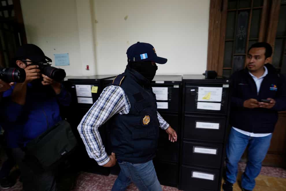 A police officer from Guatemala’s Attorney General’s office at the headquarters of the electoral authority during the raid (Moises Castillo/AP/PA)