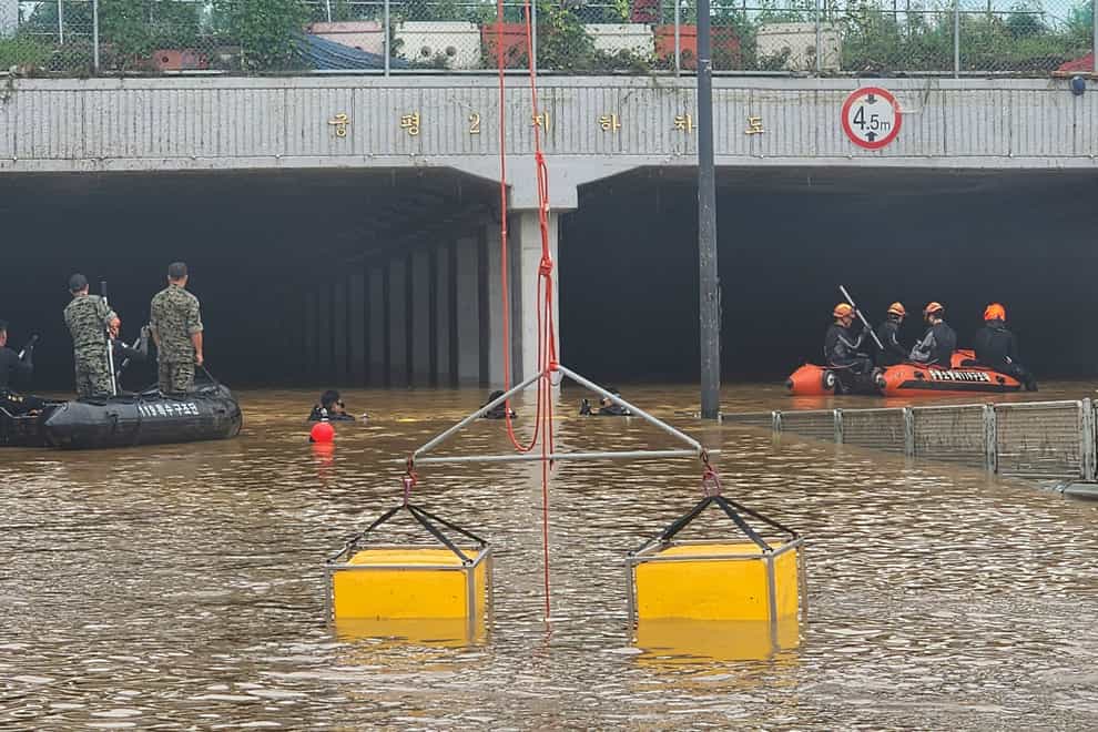 Rescuers search for survivors along a road submerged by floodwaters leading to an underground tunnel in Cheongju, South Korea (South Korea National Fire Agency via AP)