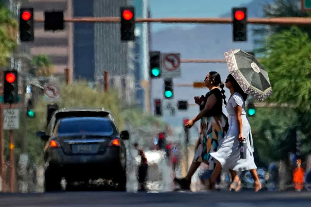 Heat ripples engulf two ladies while crossing the street in central Phoenix, Arizona (Matt York/AP)