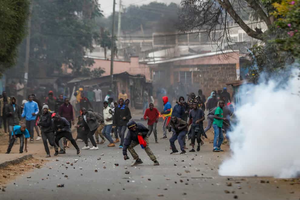 Protesters throw rocks at police during clashes next to a cloud of teargas in the Kibera area of Nairobi (AP Photo/Brian Inganga)