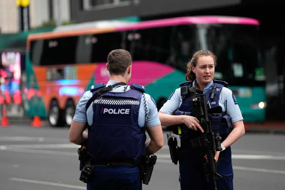 Armed New Zealand police officers stand outside a hotel housing a team from the Fifa Women’s World Cup in the central business district following a shooting in Auckland, New Zealand (Abbie Parr/AP/PA)