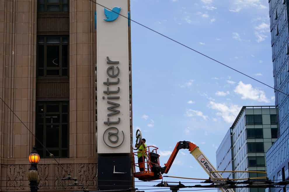 A workman removes a character from a sign on the Twitter headquarters building in San Francisco (Godofredo A Vasquez/AP)
