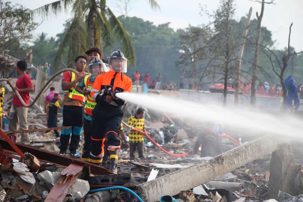 A firefighter sprays water after an explosion at a firework warehouse in Narathiwat province southern Thailand (Kriya Tehtani/AP)