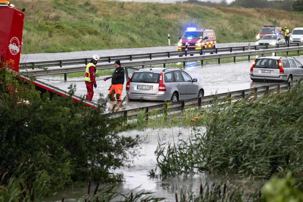 Rescue services attempt to pull out cars which got stuck in the flooded E6 road outside Malmo (TT News Agency via AP)