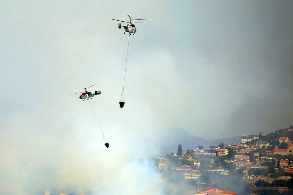 Two helicopters operate over a fire in Apesia, a semi-mountainous village near Limassol, south-western Cyprus (Philippos Christou/AP)