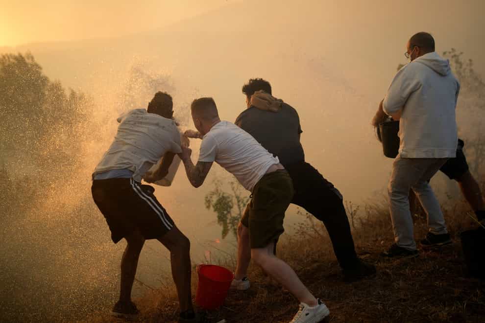 Residents use buckets of water to try to slow the flames approaching their homes in Alcabideche, outside Lisbon (Armando Franca/AP)