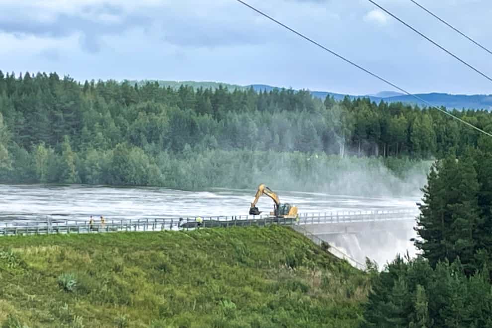 Workers reinforce a dam at risk of bursting (Bard Langvandslien/NTB Scanpix via AP)