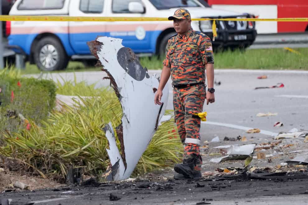 A member of the fire and rescue department inspect the crash site of a small plane in Shah Alam distric (Vincent Thian/AP)