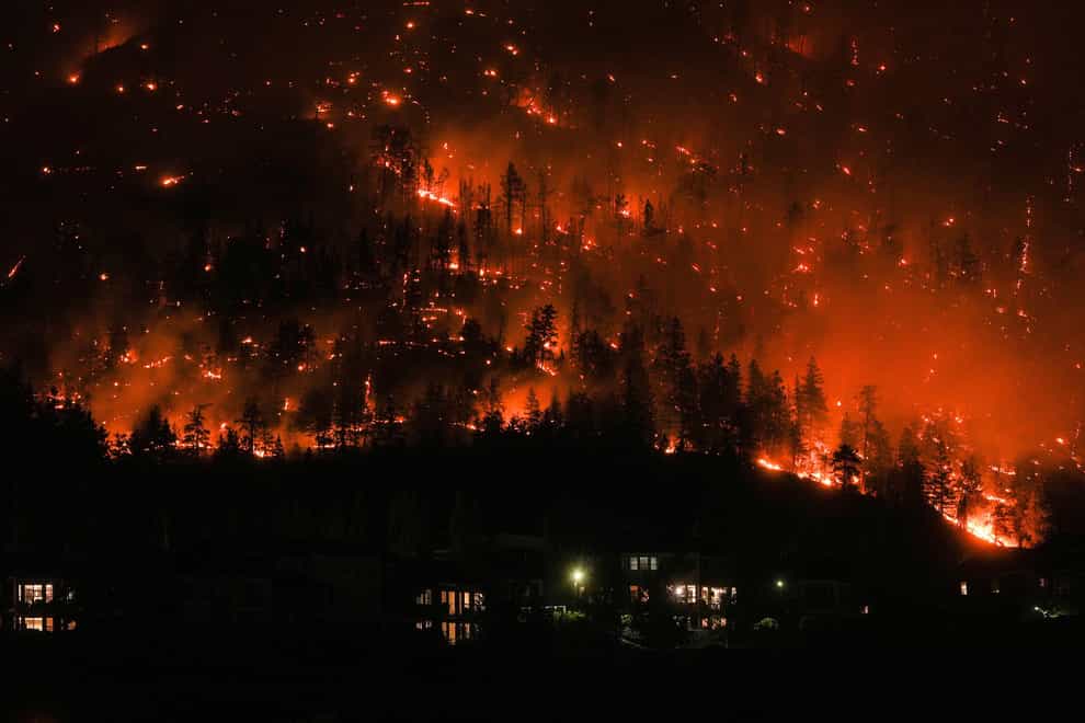 The McDougall Creek wildfire burns on the mountainside above houses in West Kelowna (Darryl Dyck/The Canadian Press via AP)