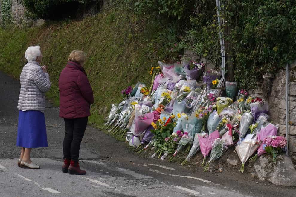Women say a prayer by flowers and tributes left at the scene in Clonmel, Co Tipperary, of a fatal car crash (Brian Lawless/PA)