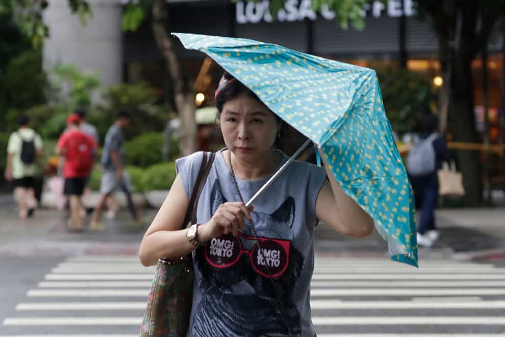 A woman struggles with her umbrella against gusts of wind generated by Typhoon Haikui in Taipei, Taiwan, on Sunday (Chiang Ying-ying/AP)