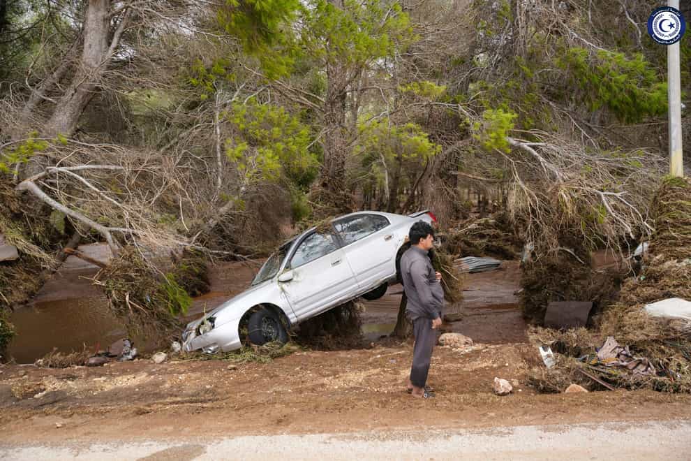 A car sits partly suspended in trees after being carried by floodwaters in Derna (Libyan government handout via AP)