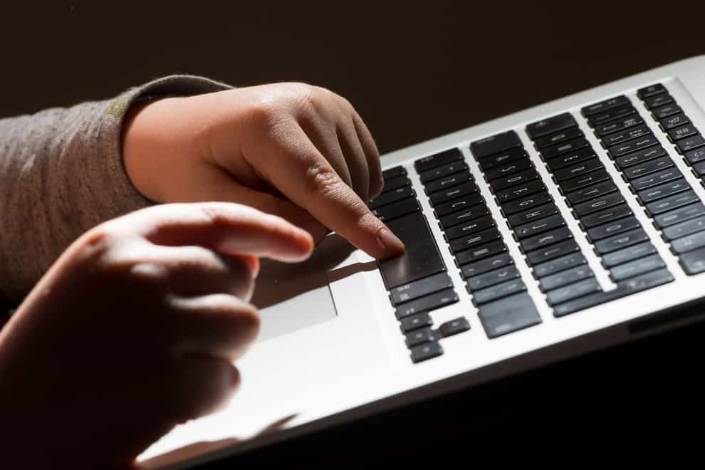 A child’s hands on the keys of a laptop keyboard.