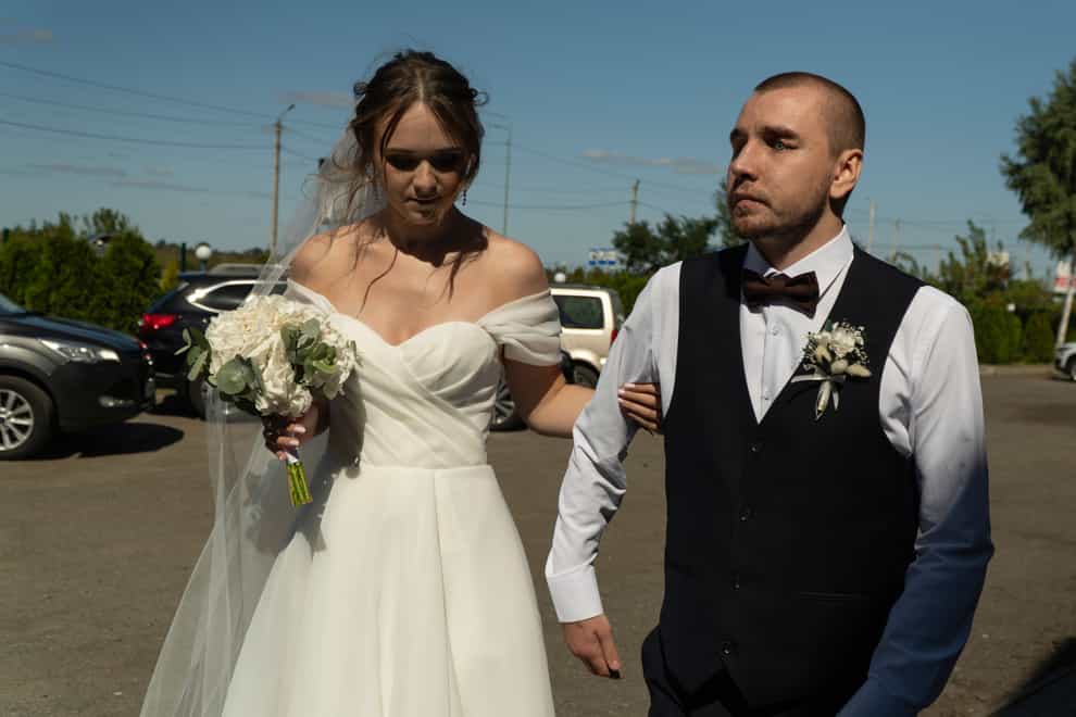 Vladislava Ryabets, left, helps groom Ivan Soroka, right, to walk during their wedding day in Kyiv, Ukraine (AP)