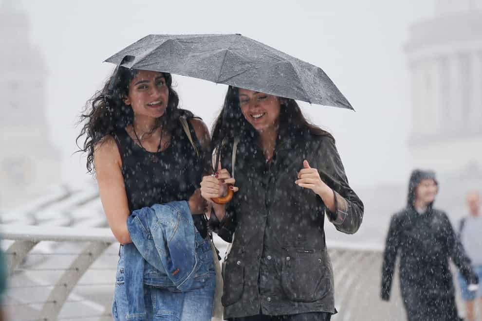 People walking along the Millennium Bridge, London, during a rain shower (Yui Mok/PA)