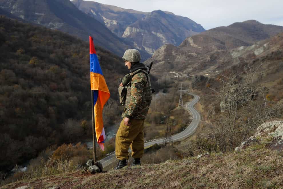 An ethnic Armenian soldier stands guard next to Nagorno-Karabakh’s flag atop of the hill near Charektar in the separatist region of Nagorno-Karabakh in 2020 (Sergei Grits/AP)