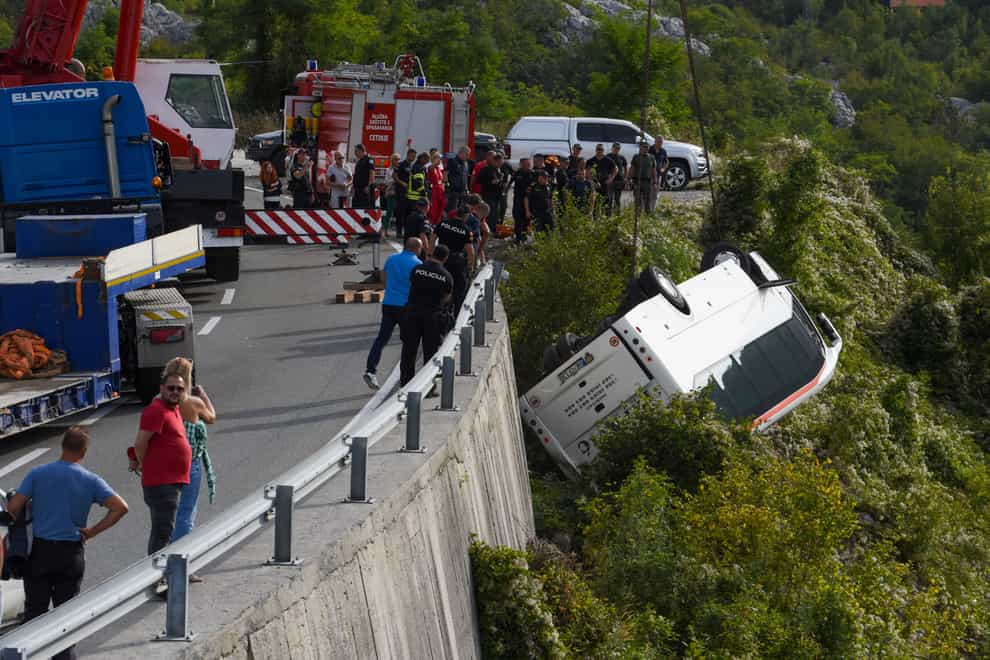 Rescue workers remove a bus at the accident site on a road near Cetinje, Montenegro (Risto Bozovic/AP/PA)