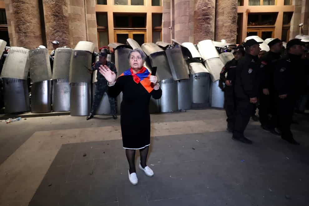 A woman with a scarf in colors of Armenian national flag gestures in front of police line during a protest against Prime Minister Nikol Pashinyan in Yerevan, Armenia, on Wednesday (Vahram Baghdasaryan/Photolure via AP/PA)